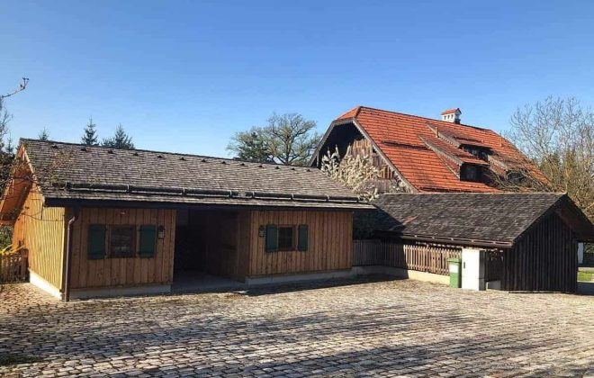 Carport und Holzhaus mit Satteldach auf gepflastertem Hof, Zimmerei Holzbau Gmachl Salzburg