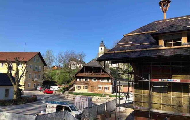 Holzbau Salzburg: Modernes Holzhaus im Bau, Zimmerei, Dachstuhl, Gerüst, sonniges Dorf