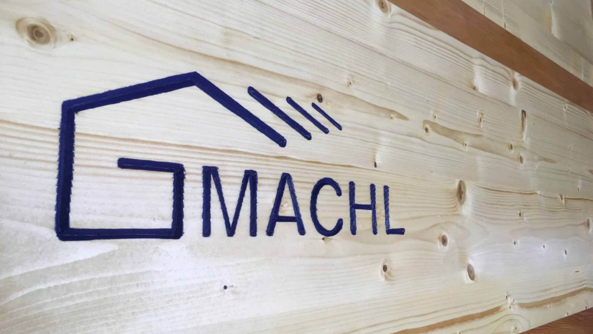Holzbau Gmachl Logo auf hellen Holzbrettern, Zimmerei Salzburg, moderner Holzbau, Dachstuhl