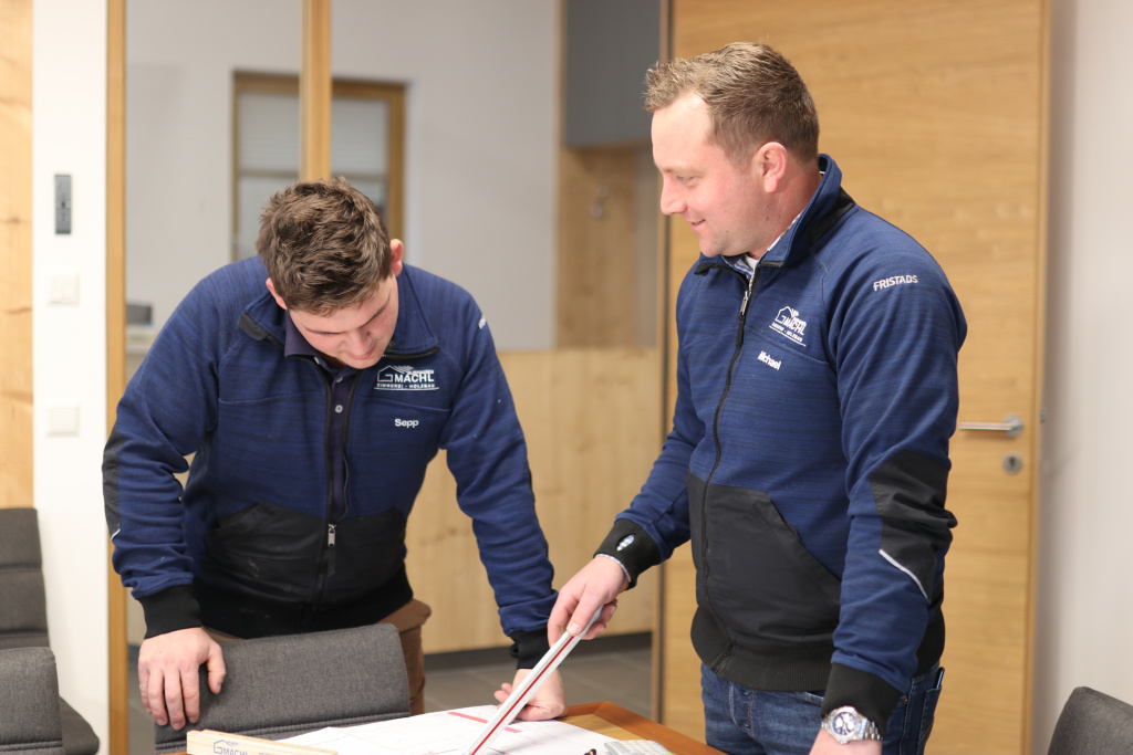 Zwei Mitarbeitende prüfen gemeinsam Baupläne im Büro.